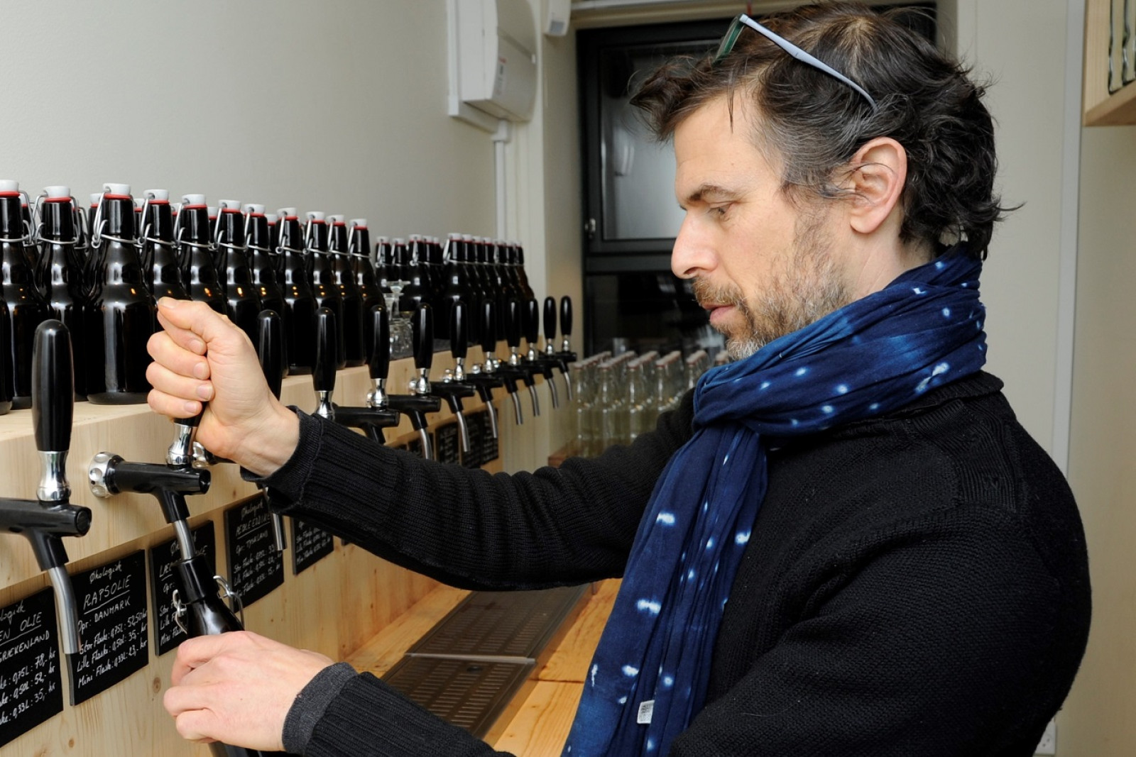 Frédéric Hamburger tapper olie på genbrugsflaske i LØS Market.